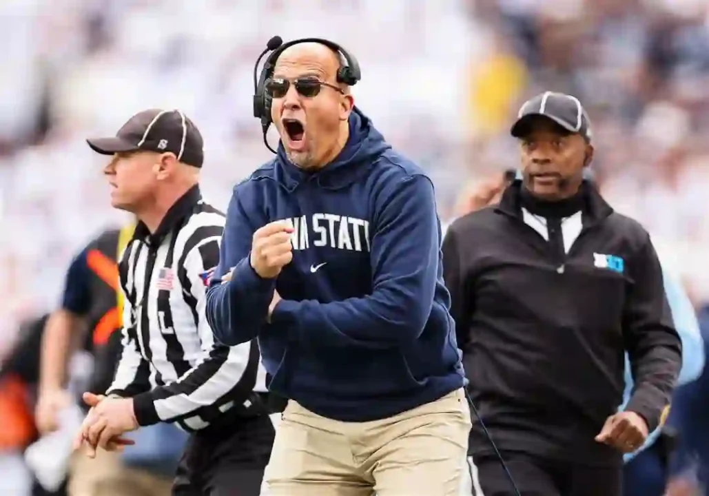 Penn State head coach James Franklin actively coaching on the sideline during a game, emphasizing his leadership role 