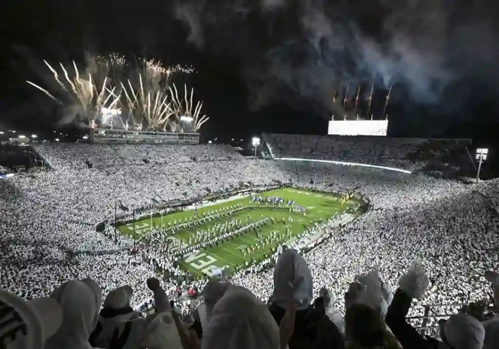 Beaver Stadium during a Penn State White Out game, filled with fans in white and fireworks illuminating the night sky 